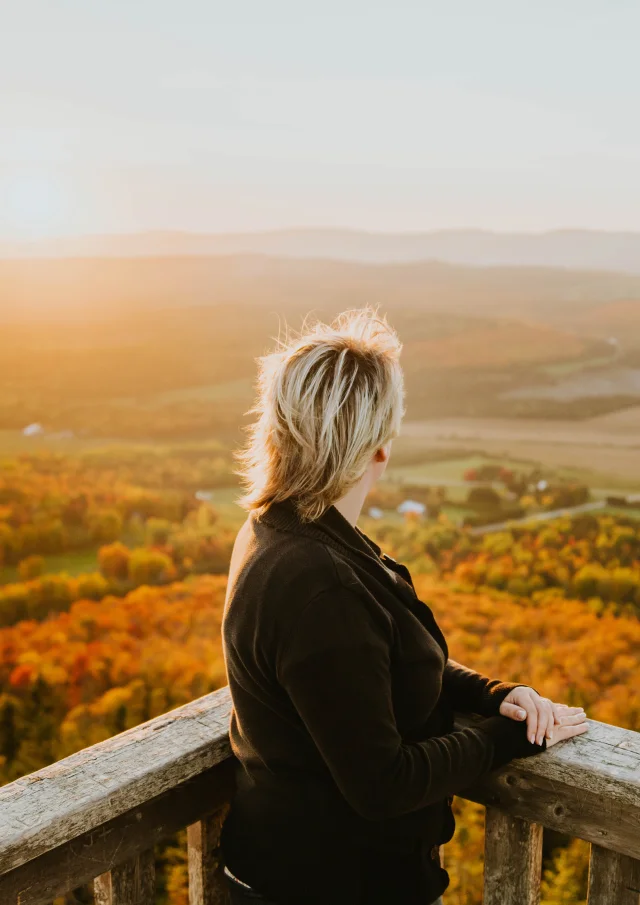 Une femme admirant le coucher de soleil à partir du belvédère situé au sommet du Mont Grand Morne à Sainte-Clotilde-de-Beauce